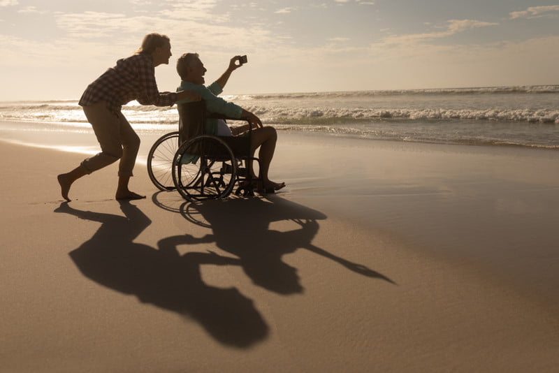 Accessible Travel: Tips and Resources for Baby Boomers with Mobility Challenges 1 retired man in wheelchair at beach